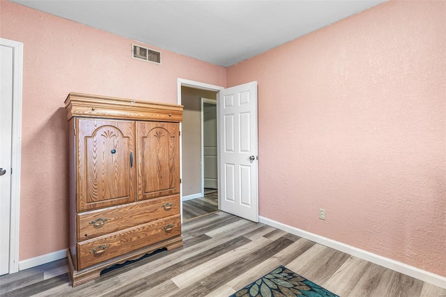 bedroom featuring light wood-style flooring, visible vents, and baseboards