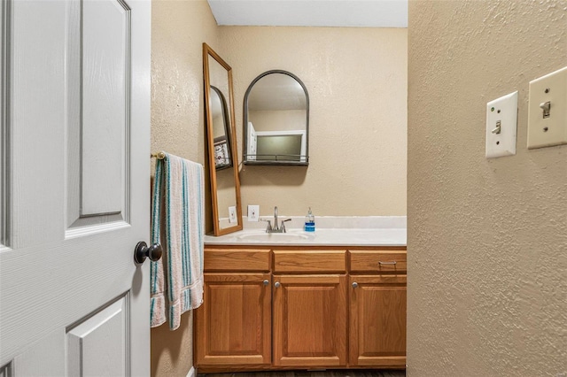 bathroom featuring a textured wall and vanity