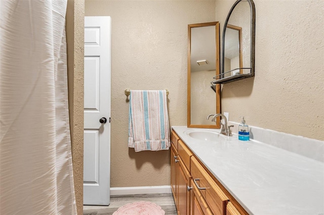 bathroom with a textured wall, vanity, and baseboards