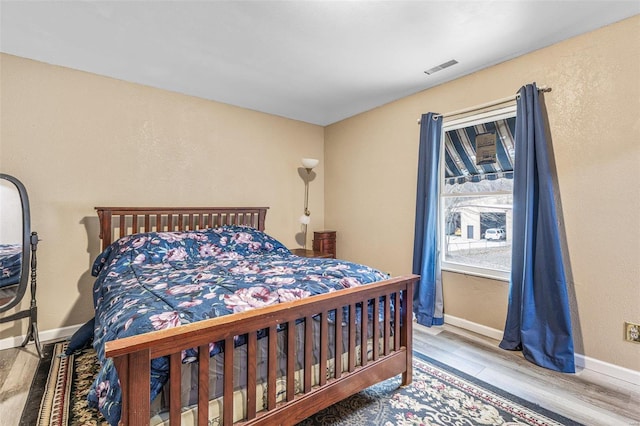 bedroom featuring baseboards, visible vents, and wood finished floors