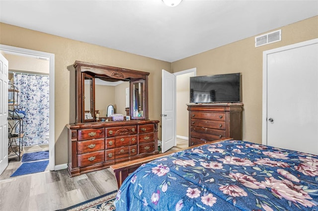 bedroom with baseboards, visible vents, and wood finished floors