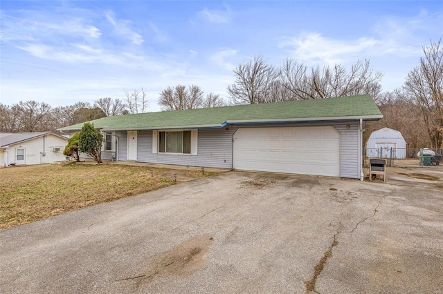 single story home featuring aphalt driveway, a front lawn, and an attached garage