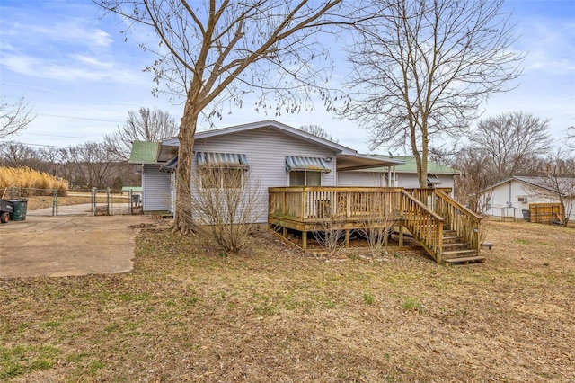 rear view of house with a wooden deck, fence, and a gate