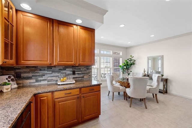 kitchen featuring tasteful backsplash, baseboards, brown cabinets, stone counters, and recessed lighting