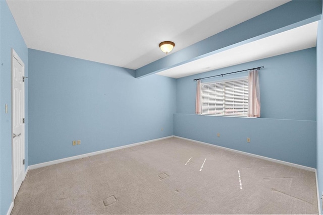 carpeted empty room featuring baseboards