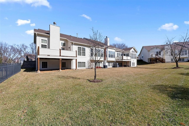 rear view of house featuring a residential view, a lawn, a chimney, and fence