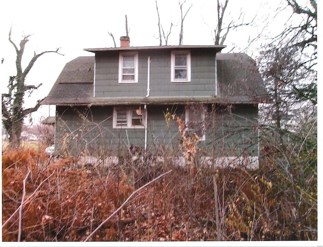 rear view of property with a shingled roof and a chimney