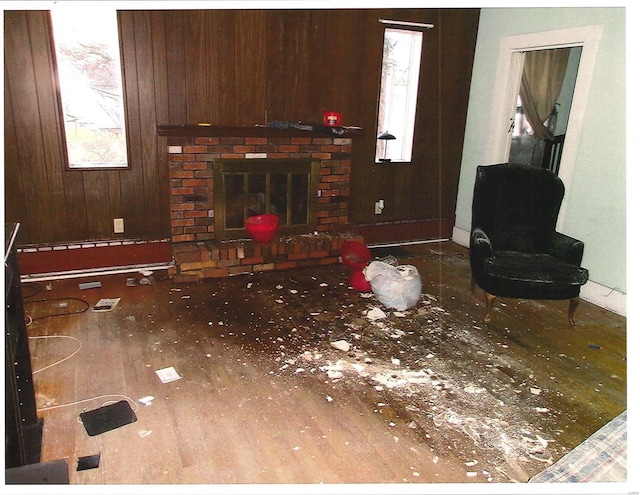 living area with a fireplace, wood finished floors, and wooden walls