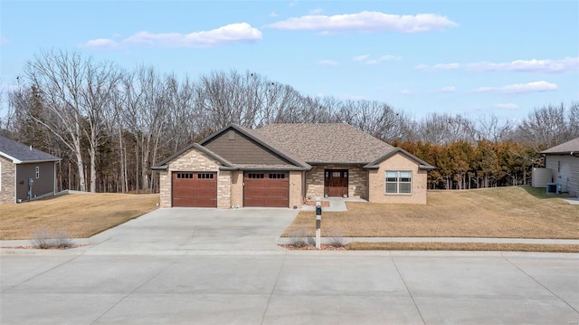 view of front of property with a garage, roof with shingles, concrete driveway, and a front lawn