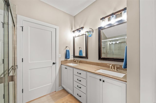 bathroom featuring double vanity, a shower stall, and a sink