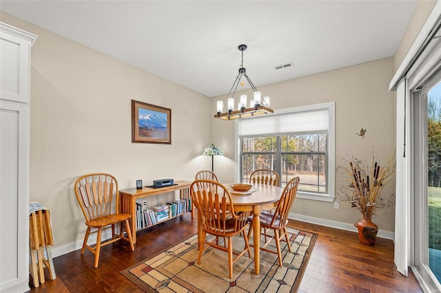 dining area featuring hardwood / wood-style floors, an inviting chandelier, baseboards, and visible vents