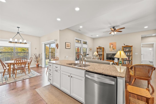 kitchen featuring a kitchen island with sink, a sink, white cabinets, light wood-style floors, and dishwasher