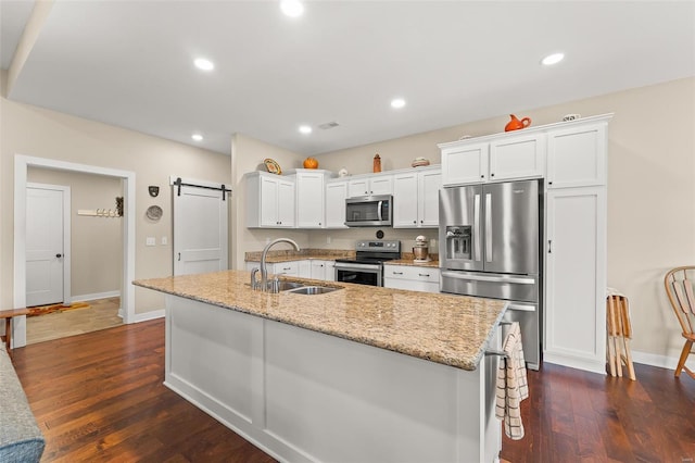 kitchen with dark wood-style floors, a sink, appliances with stainless steel finishes, white cabinetry, and a barn door