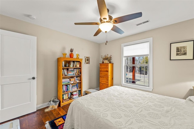 bedroom with visible vents, baseboards, a ceiling fan, and hardwood / wood-style flooring