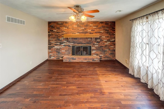 unfurnished living room with a ceiling fan, a fireplace, visible vents, and wood finished floors