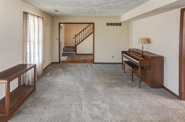 sitting room with stairway, carpet, visible vents, and baseboards