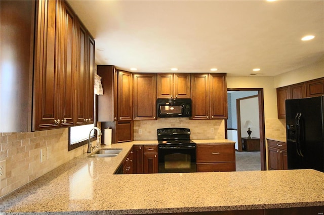 kitchen featuring light stone countertops, recessed lighting, a sink, decorative backsplash, and black appliances