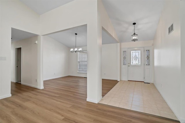 foyer entrance with a notable chandelier, visible vents, light wood-style flooring, and lofted ceiling