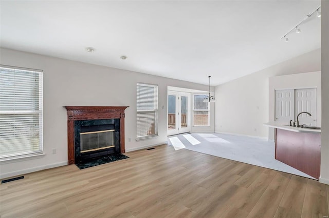 unfurnished living room with visible vents, a premium fireplace, plenty of natural light, a sink, and light wood-style floors