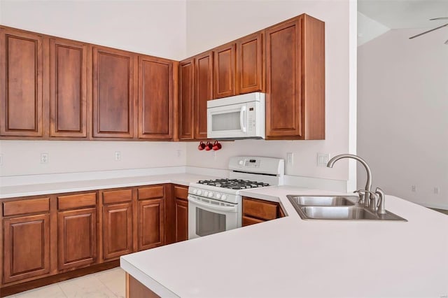 kitchen featuring light countertops, lofted ceiling, a peninsula, white appliances, and a sink