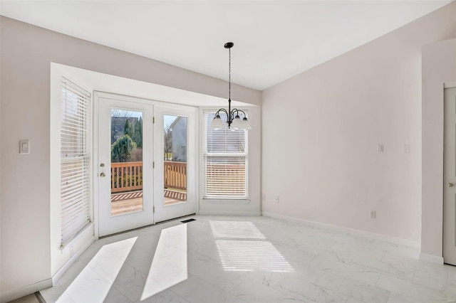 unfurnished dining area featuring a wealth of natural light, a chandelier, marble finish floor, and baseboards