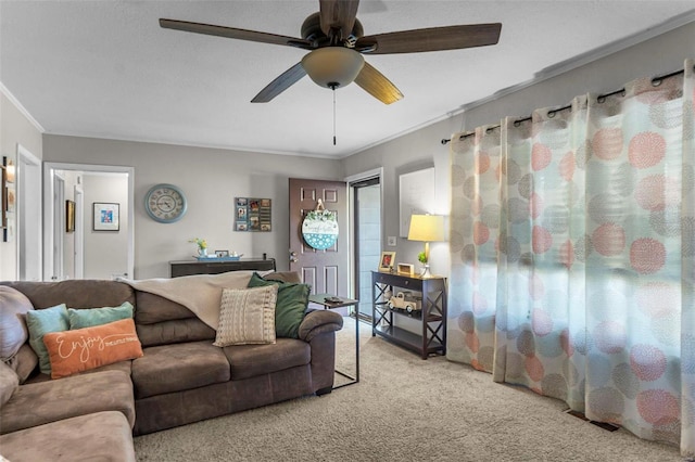 living area with ceiling fan, ornamental molding, carpet, and visible vents