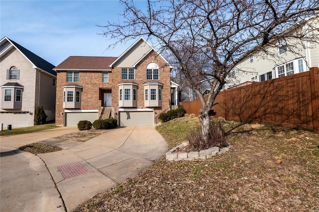 view of front of property with a garage, driveway, brick siding, and fence