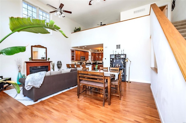 dining area featuring ceiling fan, light wood-type flooring, a fireplace, and visible vents