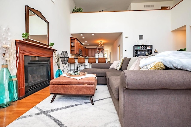 living room with recessed lighting, light wood-style flooring, visible vents, and a glass covered fireplace