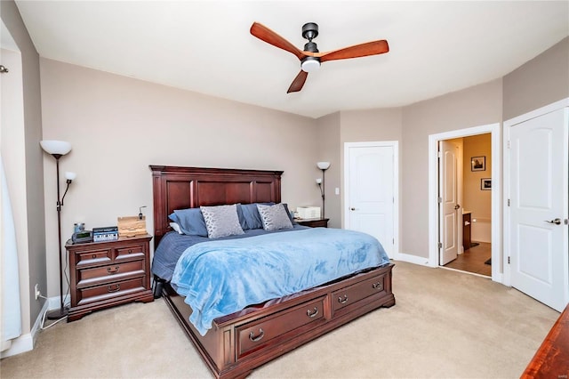 bedroom with light colored carpet, ceiling fan, ensuite bath, and baseboards