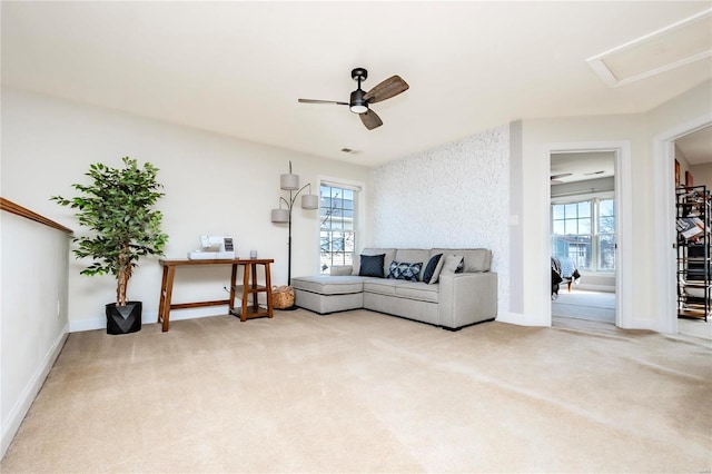 living area featuring plenty of natural light, baseboards, ceiling fan, and light colored carpet