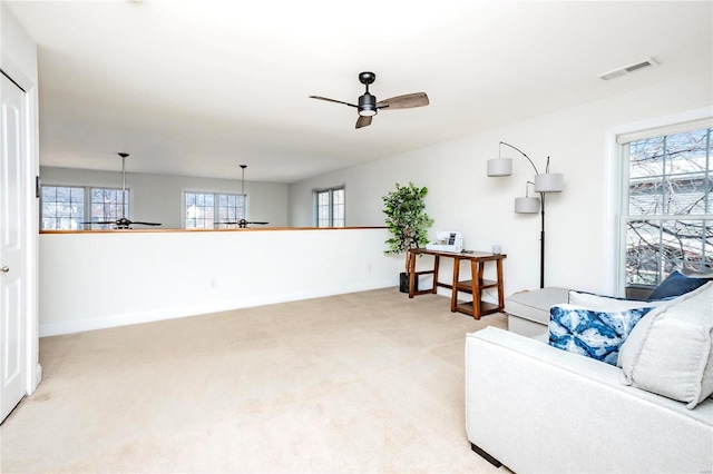 living area featuring a ceiling fan, visible vents, light carpet, and baseboards