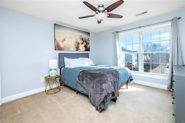 bedroom featuring light colored carpet, ceiling fan, visible vents, and baseboards