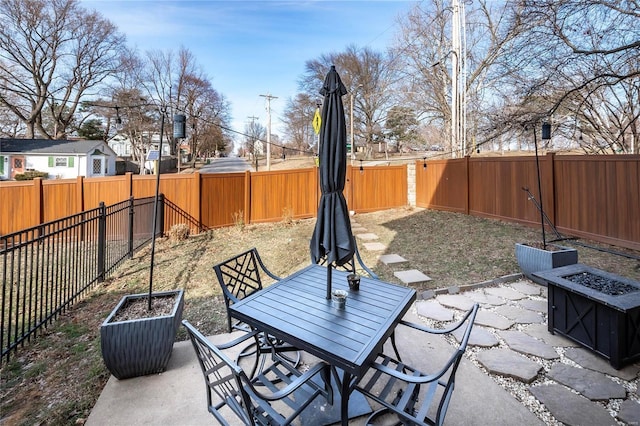 view of patio with a fire pit, outdoor dining space, and a fenced backyard