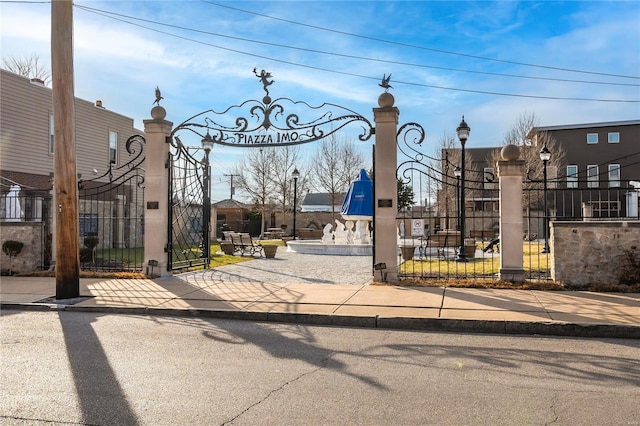 view of street featuring a gate, curbs, and street lights