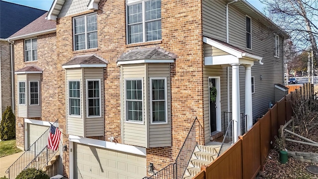 back of house featuring an attached garage, fence, and brick siding