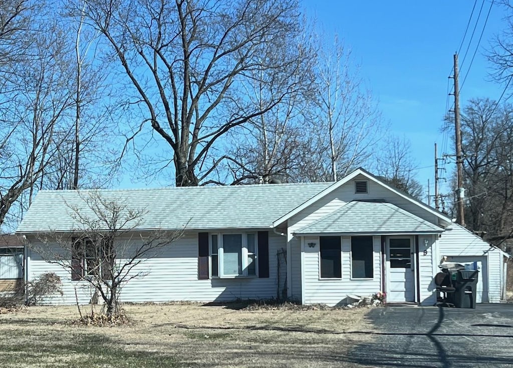 ranch-style house with a garage, roof with shingles, and driveway