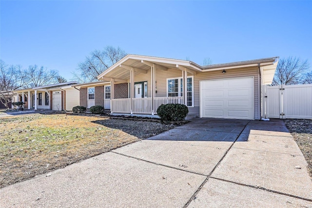 single story home featuring an attached garage, covered porch, a gate, and concrete driveway