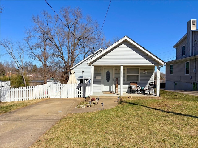 bungalow-style home with covered porch, a fenced front yard, and a front lawn