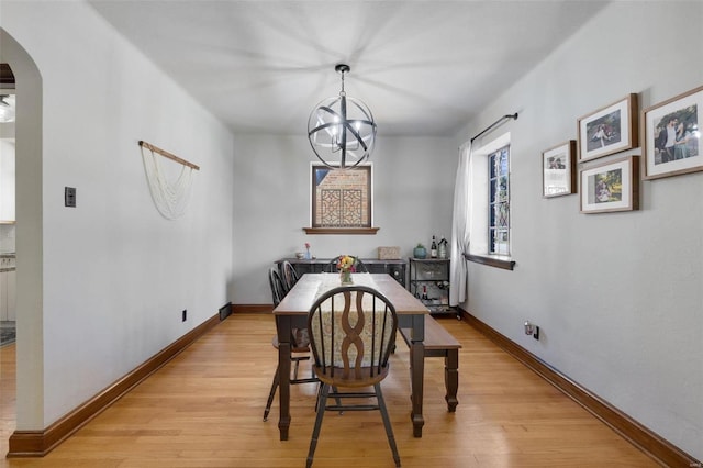 dining space with light wood finished floors, baseboards, and arched walkways