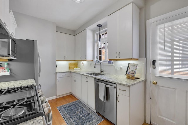 kitchen featuring appliances with stainless steel finishes, white cabinetry, and a sink