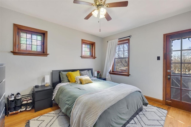 bedroom featuring access to exterior, wood finished floors, a ceiling fan, and baseboards