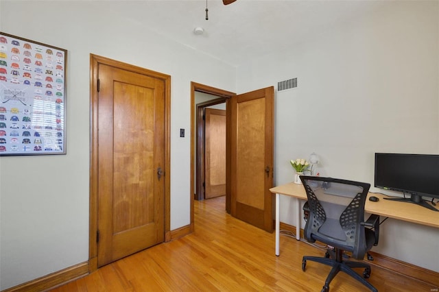 office space with light wood-type flooring, visible vents, ceiling fan, and baseboards