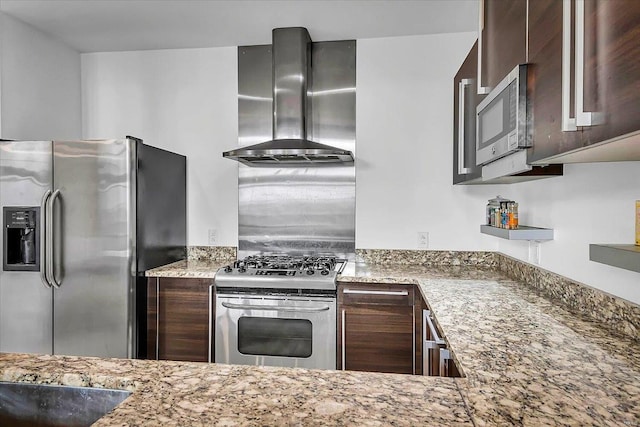 kitchen with appliances with stainless steel finishes, dark brown cabinetry, wall chimney exhaust hood, and light stone countertops