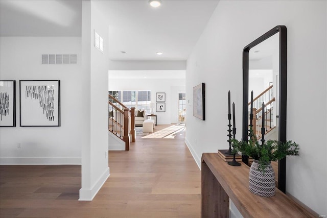 hallway with baseboards, visible vents, wood finished floors, stairs, and recessed lighting