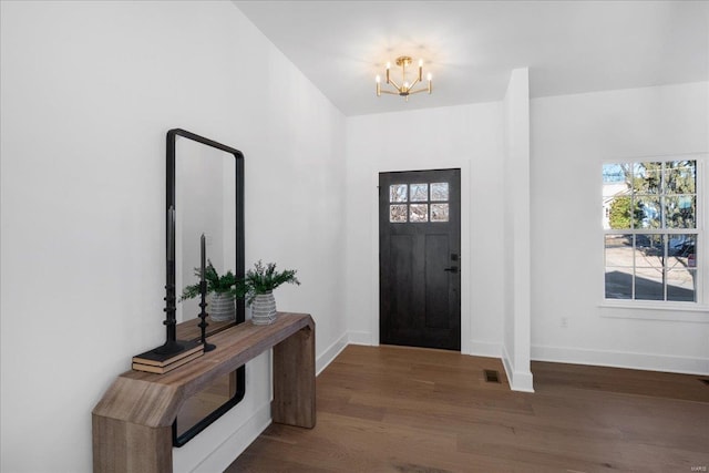 entrance foyer with visible vents, a notable chandelier, baseboards, and wood finished floors