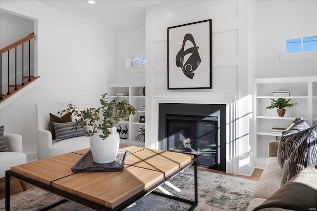 living area featuring recessed lighting, plenty of natural light, stairway, and a glass covered fireplace