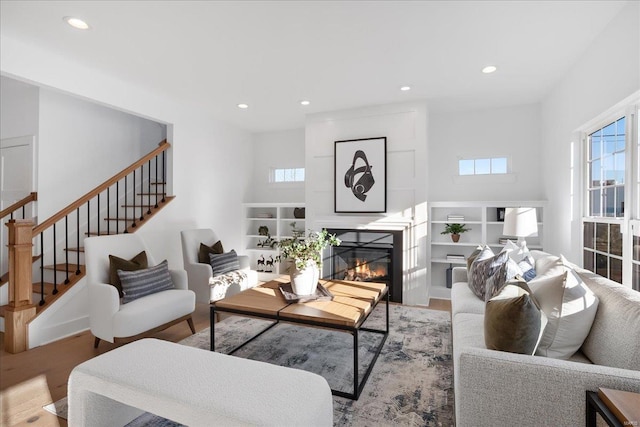 living room featuring recessed lighting, stairs, and a glass covered fireplace