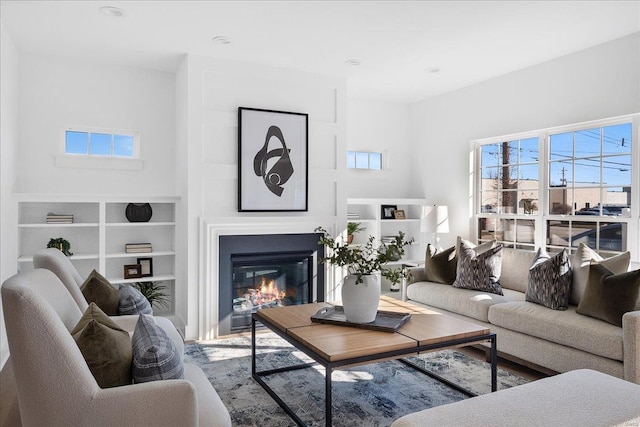 living room featuring a healthy amount of sunlight and a glass covered fireplace