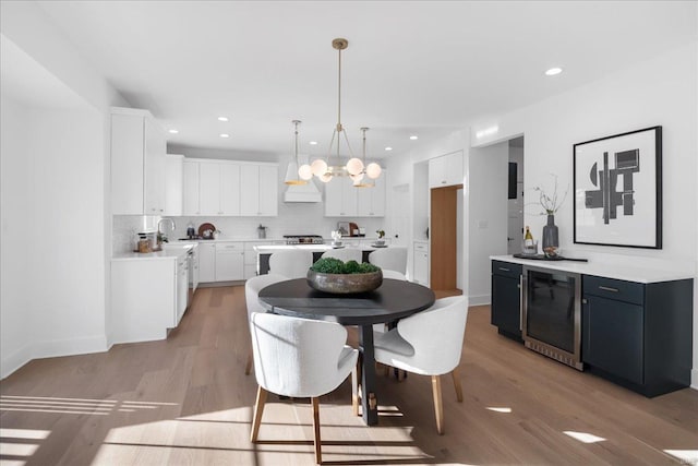 kitchen featuring light wood-style floors, beverage cooler, white cabinetry, and decorative backsplash